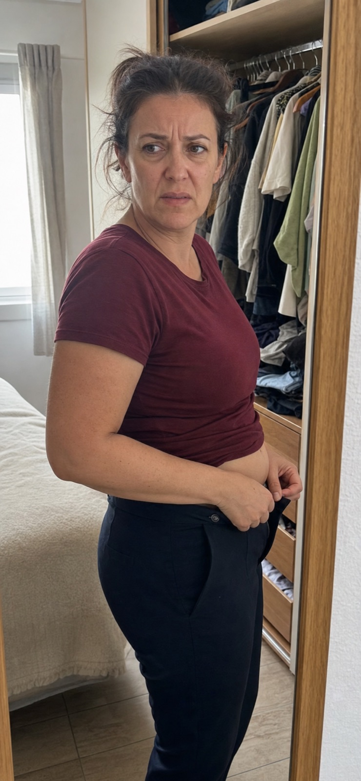 Mujer intentando abrocharse un pantalón delante del armario